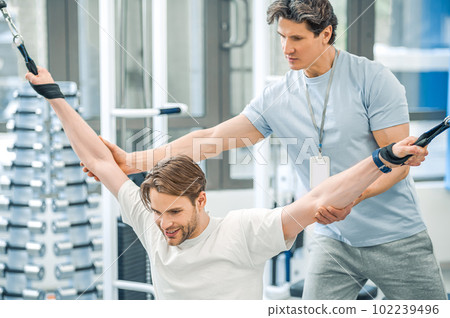 Physical therapist assisting a patient while exercising on hyperextension 102239496