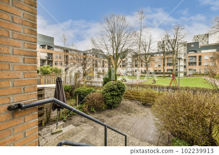 an outside area with trees and bushes in the foreground, taken from a window looking out onto some buildings an outside area with trees and bushes in the foreground, taken from a window looking out onto some buildings 102239913