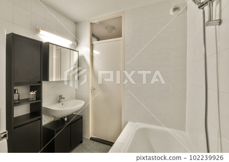 a bathroom with a sink, mirror and bathtub in the corner next to the shower stall is white tiles on the floor 102239926
