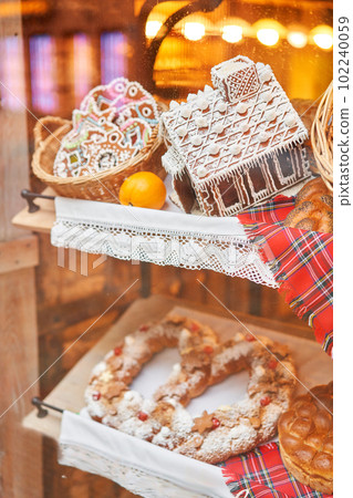 A bakery showcase in a European city for Christmas. Gingerbread house, pretzel, apple crumble, buns. Bread on Christmas and New year A bakery showcase in a European city for Christmas. Gingerbread house, pretzel, apple crumble, buns. Bread on Christmas and New year 102240059