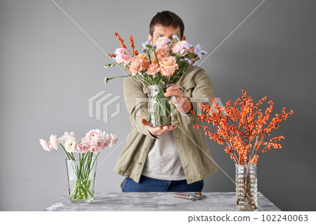 Portrait of a Male florist. Flowers bunch, set for home. Fresh cut flowers for decoration home. European floral shop. Delivery fresh cut flower. Portrait of a Male florist. Flowers bunch, set for home. Fresh cut flowers for decoration home. European floral shop. Delivery fresh cut flower. 102240063