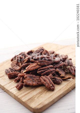 Tasty pecan-nut on a wooden board on white color table Tasty pecan-nut on a wooden board on white color table 102240381