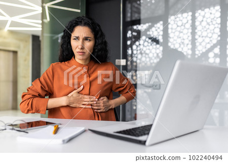 Anxious and scared business woman working inside office, Hispanic woman panic attack and breathing problem, female worker with laptop working. 102240494