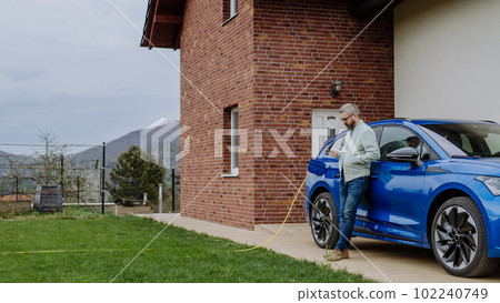 Mature businessman waiting for charging his electric car. 102240749