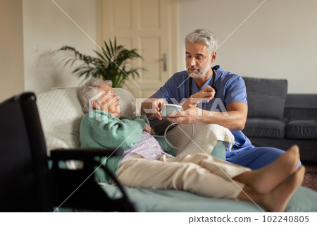 Caregiver doing regular check-up of senior woman in her home. 102240805