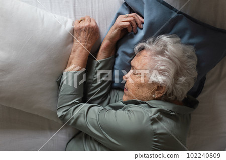 Senior woman sleeping in her bed, top view. 102240809