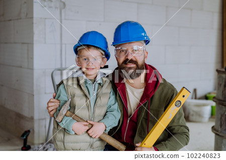 Portrait of father and his little son in their unfinished house. 102240823