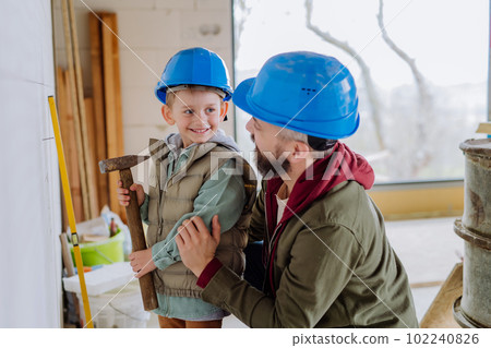 Father and his little son working on their unfinished house. 102240826