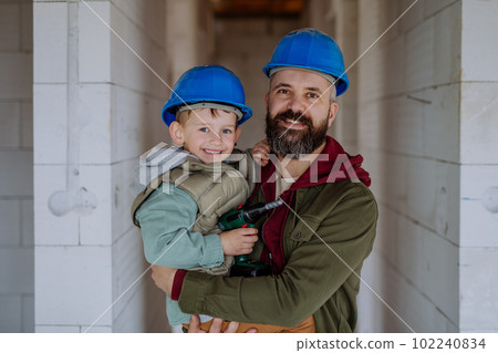 Portrait of father and his little son in their unfinished house. Portrait of father and his little son in their unfinished house. 102240834