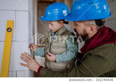 Father and his little son working on their unfinished house. Father and his little son working on their unfinished house. 102240836