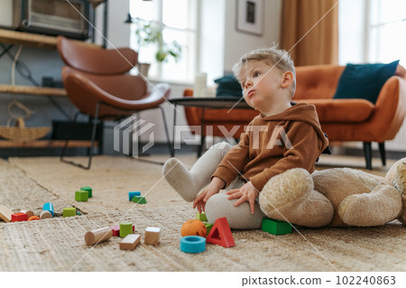 Little boy sitting on a carpet and playing with the cubes. Little boy sitting on a carpet and playing with the cubes. 102240863