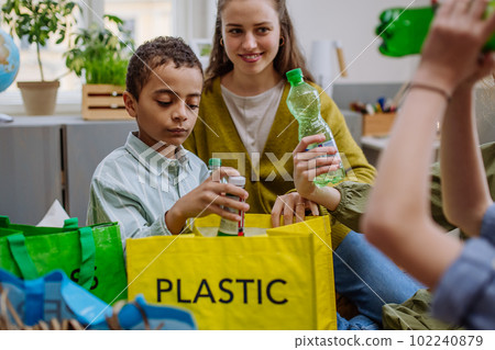 Children with teacher separating rubish in to three bins. 102240879