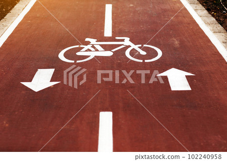 New marking bike path. White bicycle symbol and two oposite arrows on red asphalt lane, road. Bicycle path in the city. Two-way cycle lane on an avenue. Lifestyle. Urban traffic and transportation 102240958