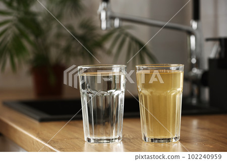 House water filtration system to drinkable condition. Glass of clear water after reverse osmos filtration and glass of dirty water on tabletop on kitchen. Evidence of contamination of tap water 102240959