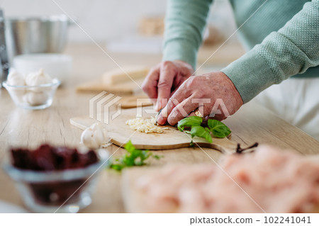Close up of senior man cutting garlic. Close up of senior man cutting garlic. 102241041