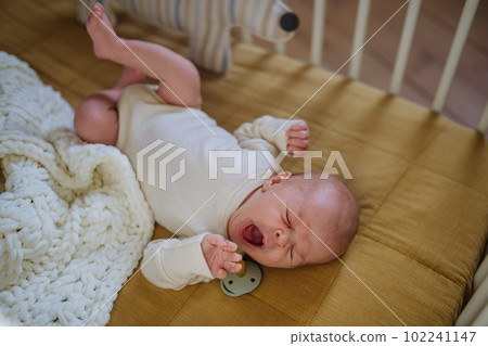High angle view of yawning baby in little bed. 102241147
