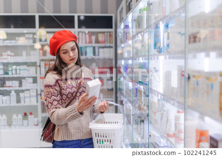 Young woman choosing a medication in pharmacy store. 102241245