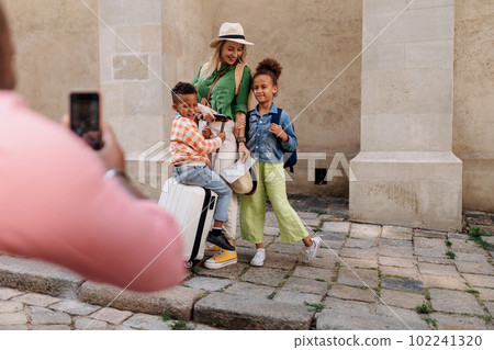 Multiracial family travelling together with small kids. Taking photo in old city cetre. Multiracial family travelling together with small kids. Taking photo in old city cetre. 102241320