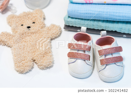 Baby girl pink shoes with other newborn baby accessories on white surface. Baby concept Baby girl pink shoes with other newborn baby accessories on white surface. Baby concept 102241482