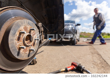 Car on tire mounting with removed wheel on pneumatic jack, seasonal tire change, car service concept. 102242144