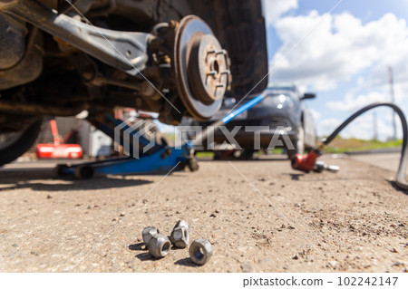 Car on tire mounting with removed wheel on pneumatic jack, seasonal tire change, car service concept. Car on tire mounting with removed wheel on pneumatic jack, seasonal tire change, car service concept. 102242147