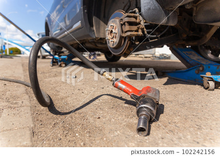 Car on tire mounting with removed wheel on pneumatic jack, seasonal tire change, car service concept. 102242156