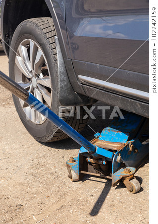 The car is raised on a pneumatic jack to change winter tires to summer tires. 102242159