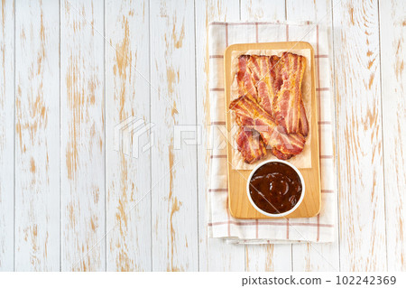 fried bacon strips and bbq sauce on a table, top view. 102242369