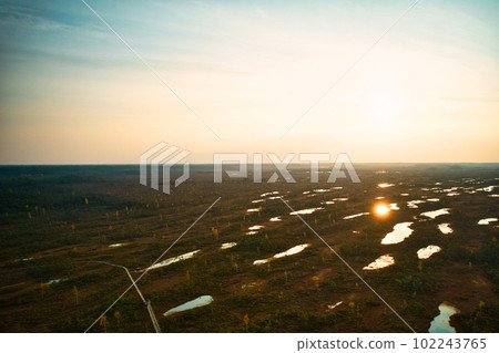 A drone photo of expansive summer swamps with winding streams, tall reeds and grasses, and green and brown wetlands. Capturing the natural serene nature scenery of this remote and unspoiled wilderness 102243765