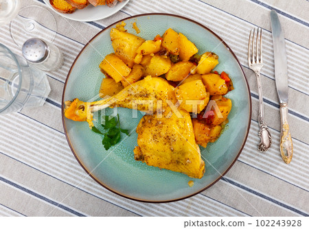 baked chicken thigh with gravy garnished with parsley and stewed potatoe and carrot 102243928