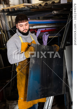 Metalworker taking steel sheet from rack 102244079