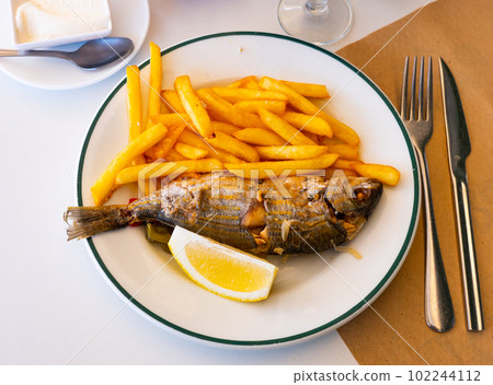 Fried sarpa salpa served with lemon and crispy fries Fried sarpa salpa served with lemon and crispy fries 102244112