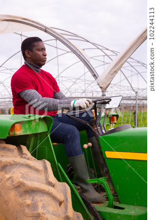 African-american worker farmer working on tractor in orangery African-american worker farmer working on tractor in orangery 102244113