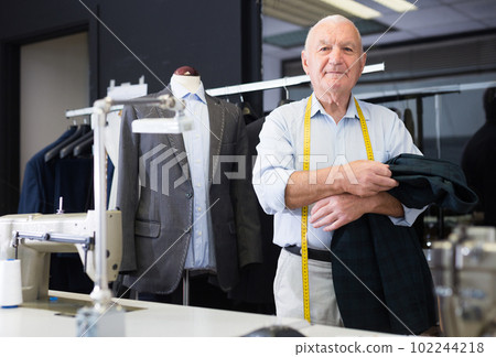 Portrait of an accomplished positive tailor with crossed arms in workshop Portrait of an accomplished positive tailor with crossed arms in workshop 102244218
