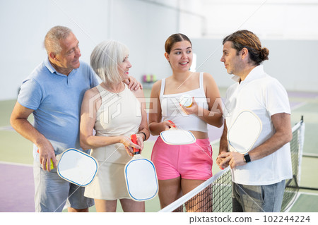 Group of smiling pickleball players talking on indoor court 102244224