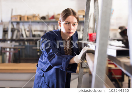 Woman worker in uniform working with metal beams 102244360