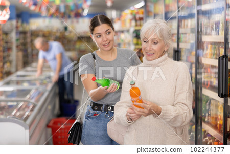 Woman purchasers choosing cool drink in big supermarket 102244377