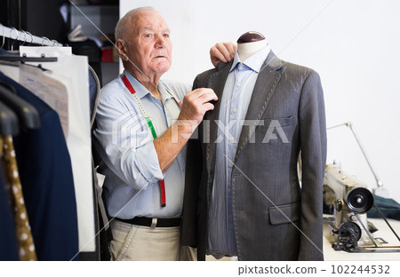 Mature tailor sews a new jacket on a mannequin in sewing studio Mature tailor sews a new jacket on a mannequin in sewing studio 102244532