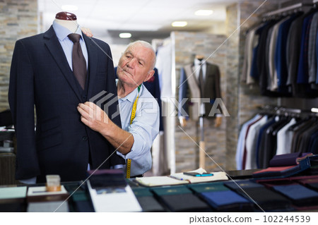 Experienced tailor tries on a new jacket on a mannequin in sewing atelier 102244539