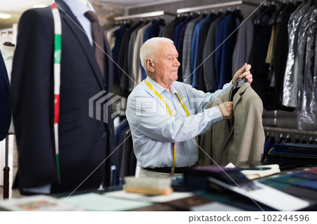 Mature tailor demonstrating of fashionable suit in apparel shop 102244596