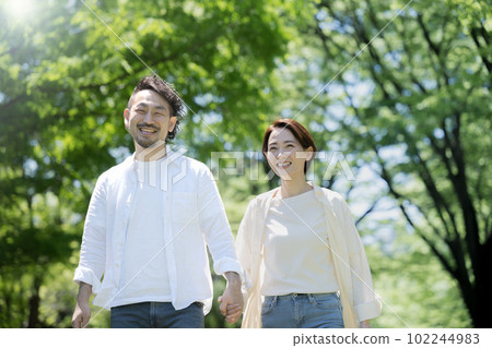 In the light, in the fresh greenery, couples walk hand in hand 102244983