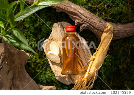Top view of glass transparent bottle filled with herbal medicine displayed on a stone. Ginseng (Panax ginseng) is an herbal medicine ingredient from Korea Top view of glass transparent bottle filled with herbal medicine displayed on a stone. Ginseng (Panax ginseng) is an herbal medicine ingredient from Korea 102245599