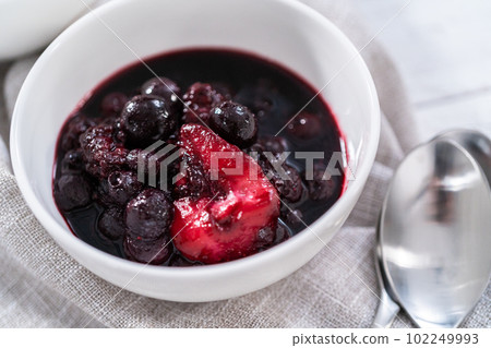 Homemade mix berry compote in small white bowls on a wooden table. Homemade mix berry compote in small white bowls on a wooden table. 102249993