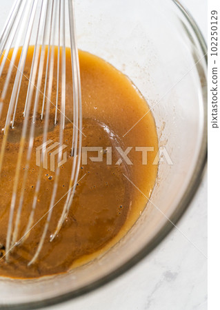 Mixing wet ingredients in a small glass mixing bowl to bake gingerbread bundt cake with caramel filling Mixing wet ingredients in a small glass mixing bowl to bake gingerbread bundt cake with caramel filling 102250129