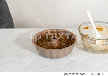 Filling metal bundt cake pan with cake butter to bake gingerbread bundt cake with caramel filling. 102250169