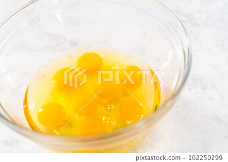 Mixing ingredients with a hand whisk in a glass mixing bowl to make egg bites. 102250299
