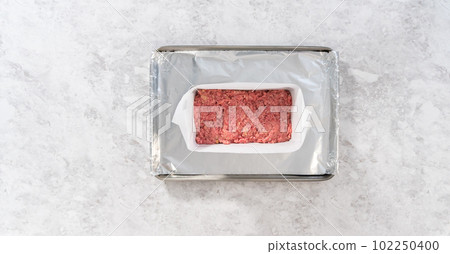 Flat lay. Preparing classic meatloaf in a loaf pan lined with parchment paper. 102250400