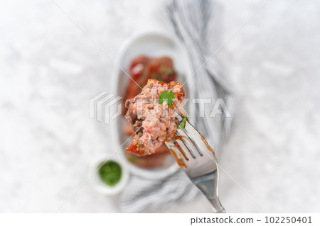 Flat lay. Slicing classic meatloaf with a sweet glaze on a white serving plate Flat lay. Slicing classic meatloaf with a sweet glaze on a white serving plate 102250401