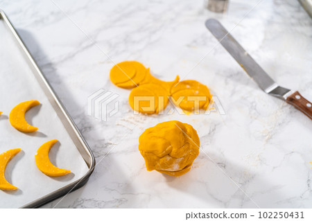 Lemon wedge cookies with lemon glaze. Rolling cookie dough with an adjustable rolling pin and cutting out cookies with cookie cutters to bake lemon wedge cookies with lemon glaze. 102250431