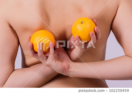 Slim woman is holding orange. Perfect female back without cellulite. Slim woman is holding orange. Perfect female back without cellulite. 102250459